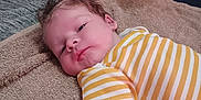 Ryker is registered to the contest to win money with this photo: baby, bed, blanket, child, cozy, curly_hair, face, indoor, infant, lying_down, person, pillow, portrait, relaxed, skin, soft_texture, striped_clothing, towel, white, yellow