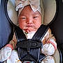 baby, infant, car_seat, headband, bow, mittens, pajamas, rainbow_pattern, straps, safety_belt, face, person, cute, indoors, soft_lighting, child, newborn, apparel, expression, seated