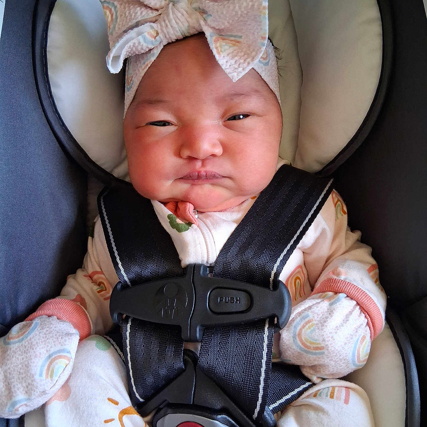 Rosèminá is registered to the contest to win money with this photo: apparel, baby, bow, car_seat, child, cute, expression, face, headband, indoors, infant, mittens, newborn, pajamas, person, rainbow_pattern, safety_belt, seated, soft_lighting, straps