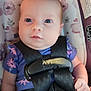 baby, car_seat, child, close_up, cute, eyes, face, floral_pattern, head, indoors, infant, looking_up, person, purple_clothing, restraint, safety_harness, seat_belt, small_hand, straps, young_child