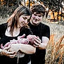 baby, newborn, couple, woman, man, outdoor, nature, field, grass, sunset, love, family, holding, portrait, people, tattoo, black_clothing, affection, trees, warm_light
