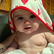 Kodie joined the competition — help win amazing prizes! baby, child, towel, hood, hearts, skin, hand, tattoo, wooden_wall, indoor, curious, chubby_cheeks, face, portrait, infant, cute, human, person, closeup, soft_lighting