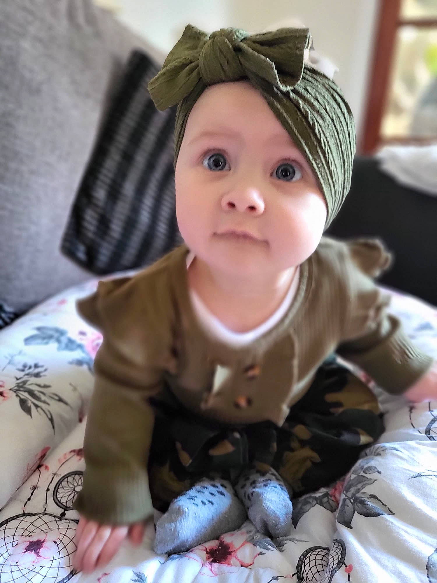 Irie is registered to the contest to win money with this photo: baby, baby_products, baby_toddler_clothing, cap, cheek, child, comfort, eye, fashion_accessory, fun, grass, headwear, iris, linens, pattern, person, room, sitting, skin, sleeve