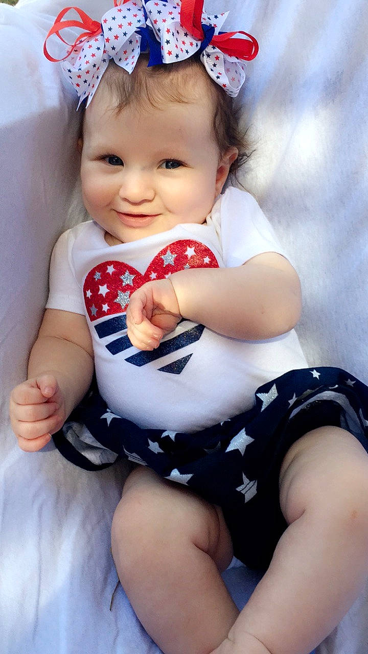 Christina is registered to the contest to win money with this photo: baby, baby_bloomers, baby_products, baby_toddler_clothing, child, hair_accessory, headband, headgear, joy, person, product, sitting, toddler