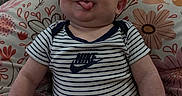 Augustus joined the competition — help win amazing prizes! baby, child, infant, onesie, striped_clothing, nike_logo, tongue_out, smiling, couch, cushion, floral_pattern, indoors, person, cute, playful, chubby_cheeks, sitting, skin, head, arms