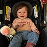 baby, smiling, car_seat, plush_toy, cow_toy, turtle_toy, child, clothing, blue_pants, pink_socks, happy, infant, person, cute, indoor, seat, head_support, warning_label, soft_toy, casual