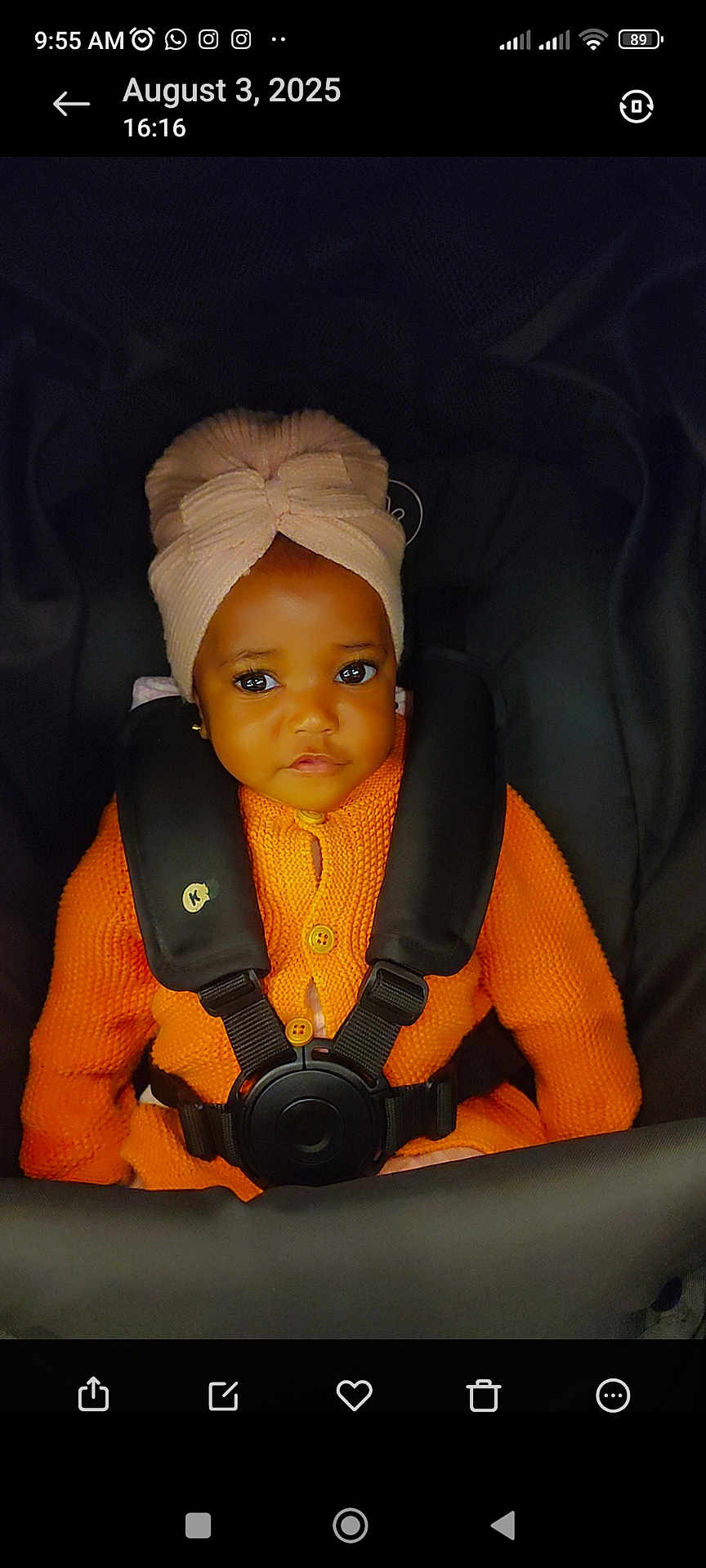 Oluwatobiloba is registered to the contest to win money with this photo: baby, child, infant, car_seat, orange_sweater, head_wrap, turban, seatbelt, cute, portrait, indoors, young_child, face, eyes, clothing, sitting, secure, adorable, warm_clothing, child_seat