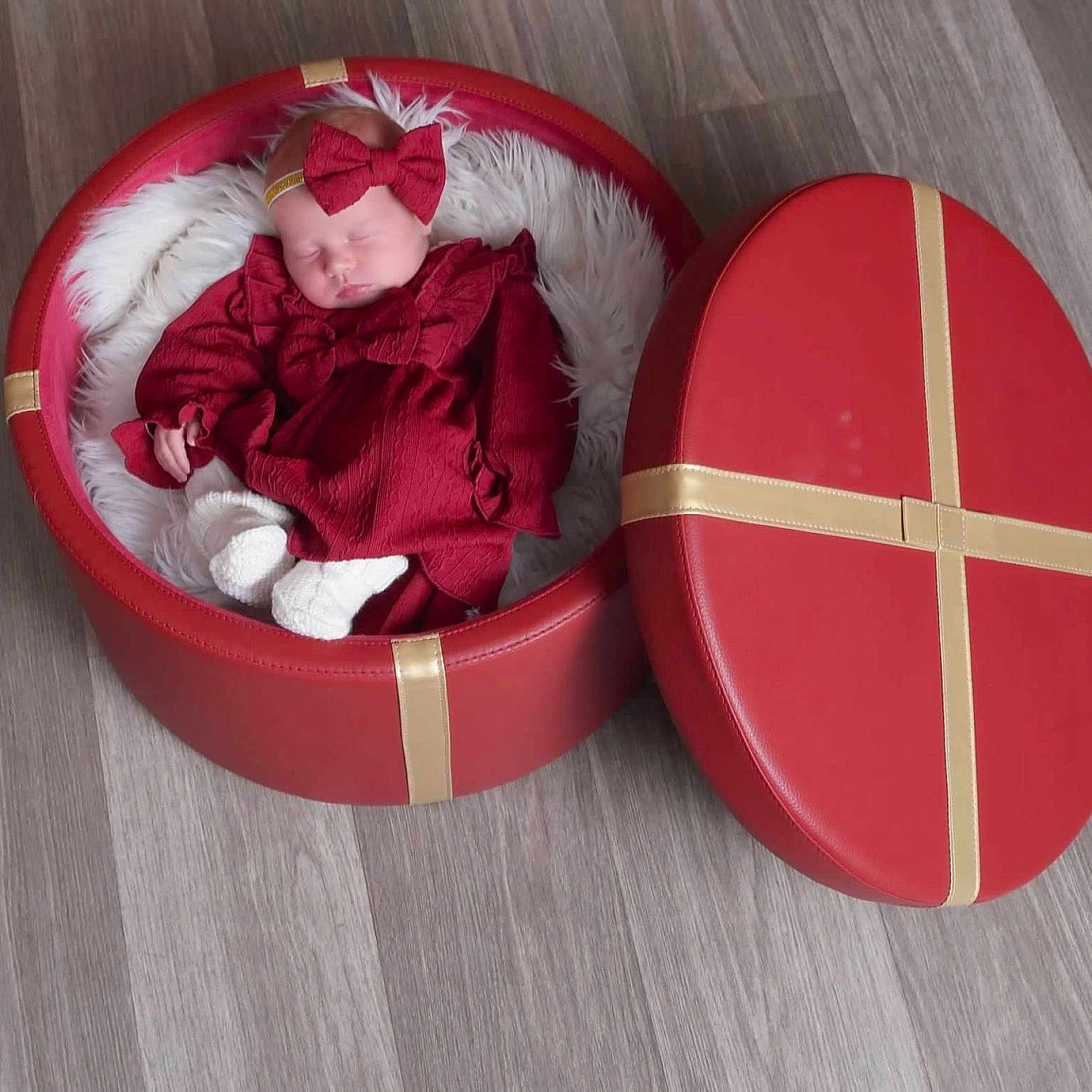 Cambria is registered to the contest to win money with this photo: baby, child, cozy, cute, floor, gift_box, headband, indoors, infant, lid, peaceful, present, red_clothing, round_box, sleeping, small, soft_texture, white_fur, wooden_floor, wrapped