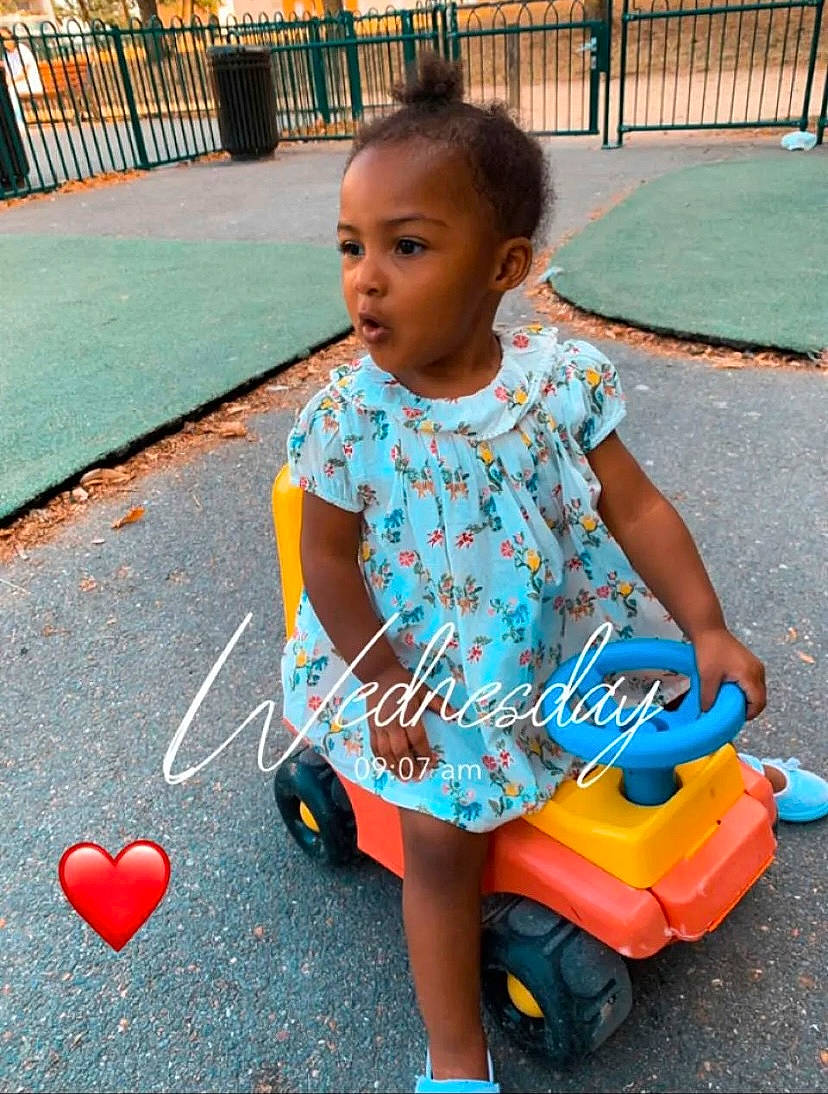 Tayana participe au concours pour gagner de l'argent avec cette photo : baby_toddler_clothing, child, dress, electric_blue, facial_expression, fun, hairstyle, happy, leisure, person, photograph, pink, public_space, recreation, red, riding_toy, snapshot, standing, tire, toddler