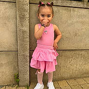 Aïyanna participe au concours pour gagner de l'argent avec cette photo : child, girl, pink_dress, hair_bows, white_sneakers, knee_high_socks, concrete_wall, pavement, smiling, posing, outdoor, playful, cute, fashion, portrait, standing, young, happy, daylight, casual