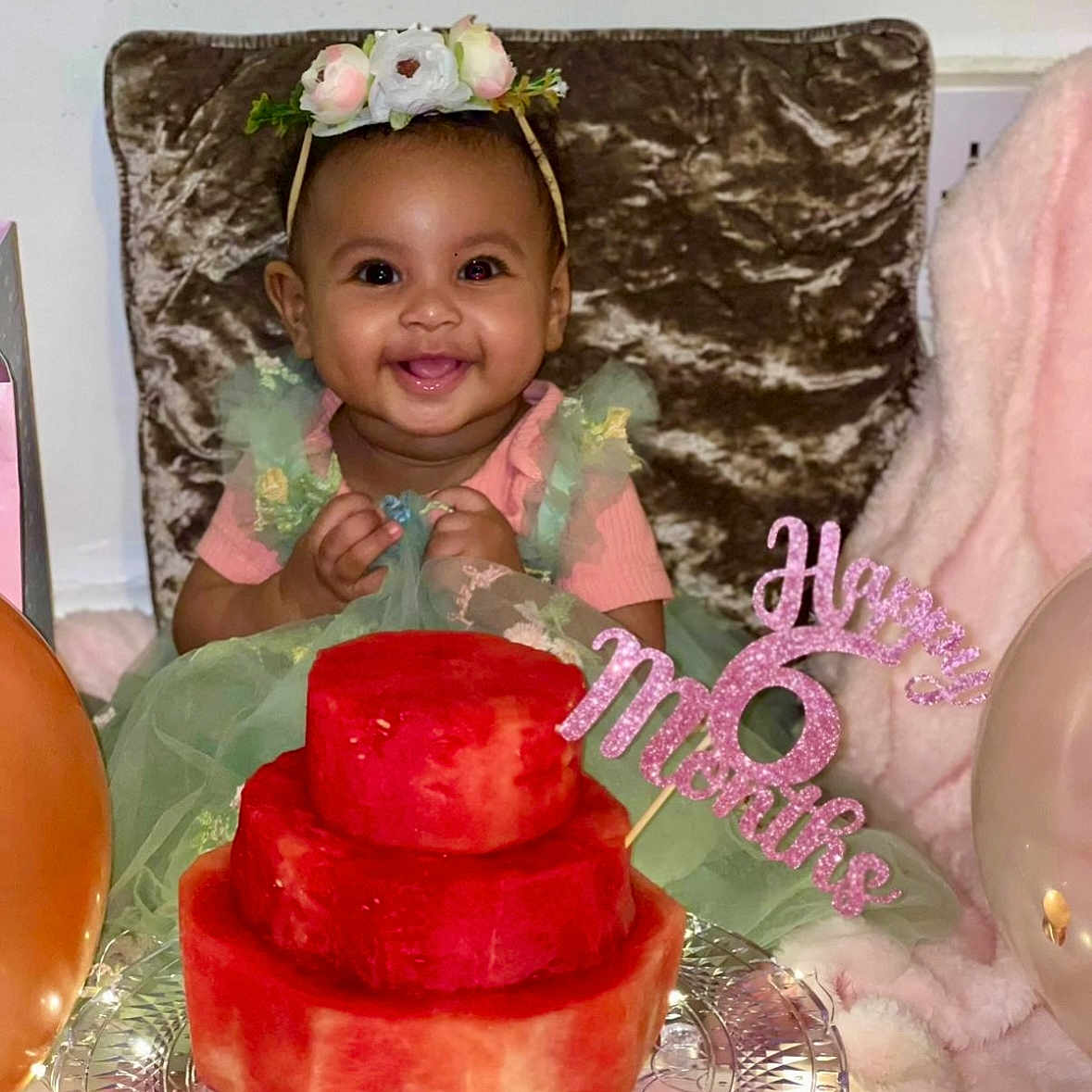 Milena is registered to the contest to win money with this photo: baby, balloons, birthday, cake, celebration, child, cozy, decor, face, flower_crown, food, green_dress, happy, party, pink, plush, portrait, sitting, smiling, watermelon_cake