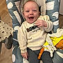 baby, smiling, child, sweater, plush_toy, baby_chair, happy, indoor, portrait, clothing, person, infant, cute, seated, cozy, fabric, soft_toy, floor, expression, young_child