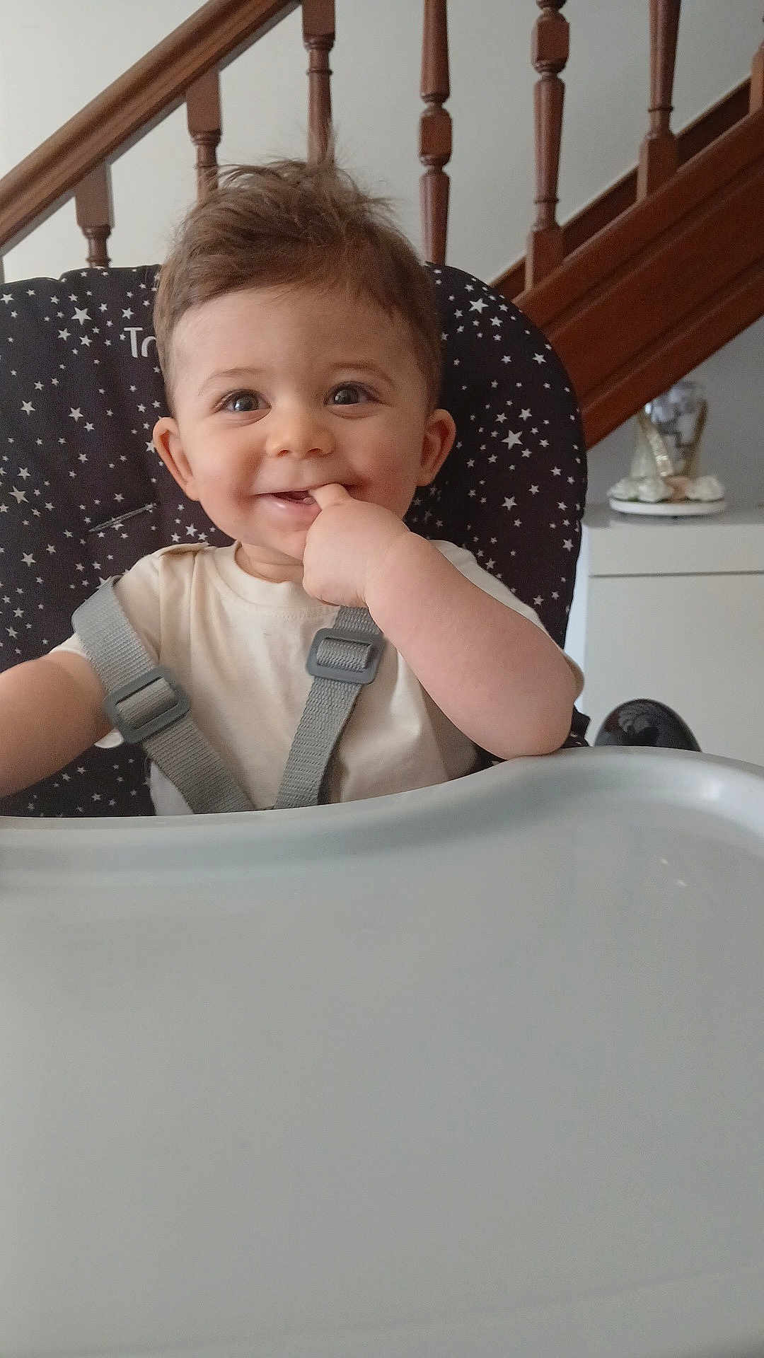 Abraham a rejoint le concours — aidez-le/la à gagner de superbes lots ! baby, infant, highchair, feeding_tray, smile, finger_in_mouth, harness, star_pattern, staircase, wooden_banister, indoor, portrait, eyes, hair, cheek, table, home, cute, happy, face