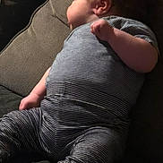 Joy participe au concours pour gagner de l'argent avec cette photo : baby, infant, striped_clothing, pajamas, couch, sofa, furniture, indoor, child, relaxing, side_view, dark_hair, soft_lighting, home, comfort, seated, blanket, footwear, sock, casual