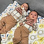 Joel-Jerimiah is registered to the contest to win money with this photo: baby, infant, twin, blanket, clothing, pants, bib, toy, wooden_beads, striped_sock, floor, carpet, couch, indoor, laying_down, cute, child, face, portrait, expression