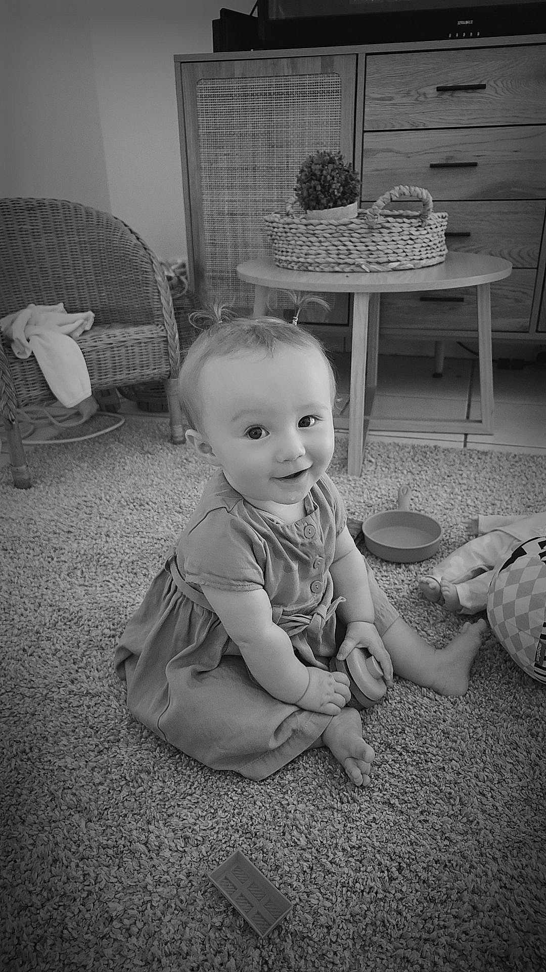 Amara a rejoint le concours — aidez-le/la à gagner de superbes lots ! baby, child, infant, sitting, carpet, toy, pigtails, smiling, indoor, furniture, wicker_chair, table, basket, plant, dress, barefoot, cushion, floor, portrait, homedecor