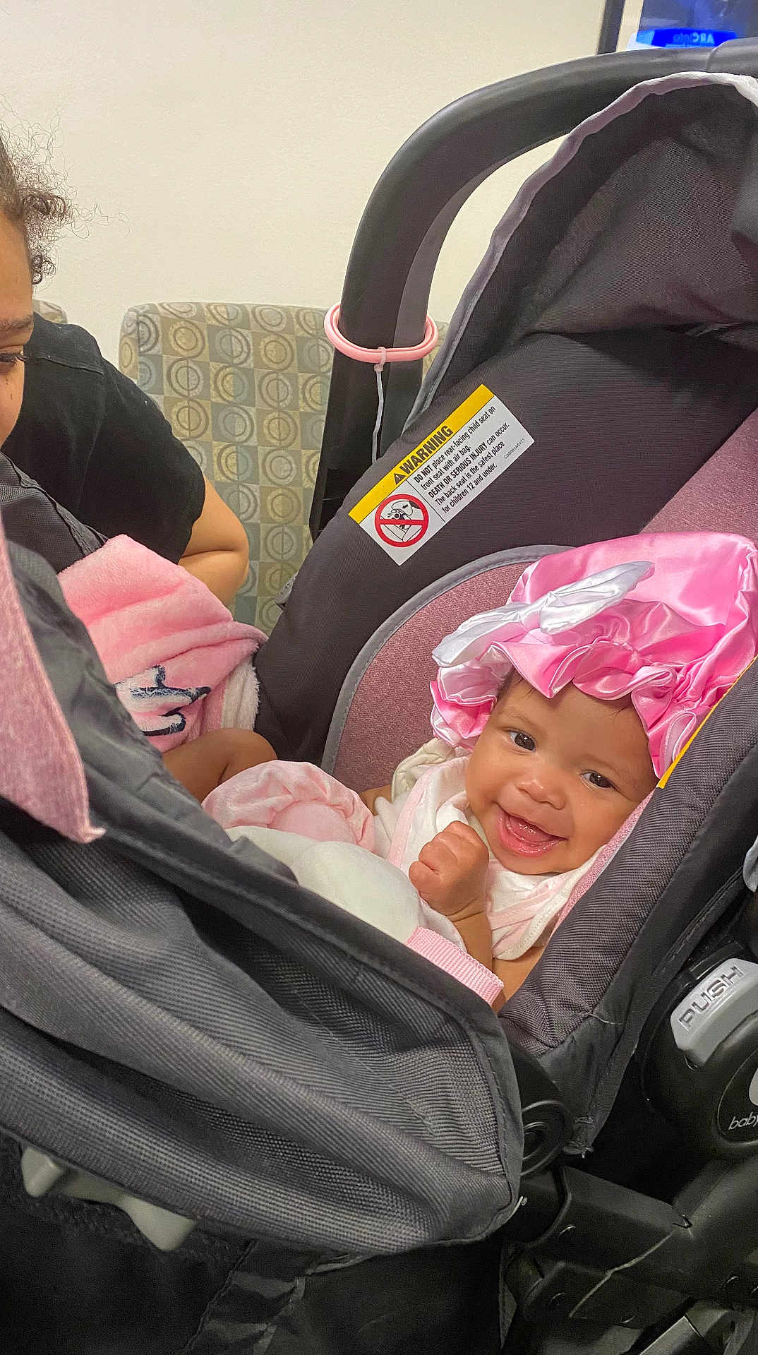 Saysri is registered to the contest to win money with this photo: baby, child, car_seat, pink_bonnet, smiling, infant, blanket, person, adult, indoor, seat, clothing, happy, cute, headwear, furniture, family, care, closeup, portrait