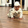 Olivia is registered to the contest to win money with this photo: baby, child, infant, crawling, portrait, flower_headband, leopard_print, outfit, sweater, floor, wood_floor, indoors, home, mirror, cabinet, furniture, play_mat, fashion, cute, photography