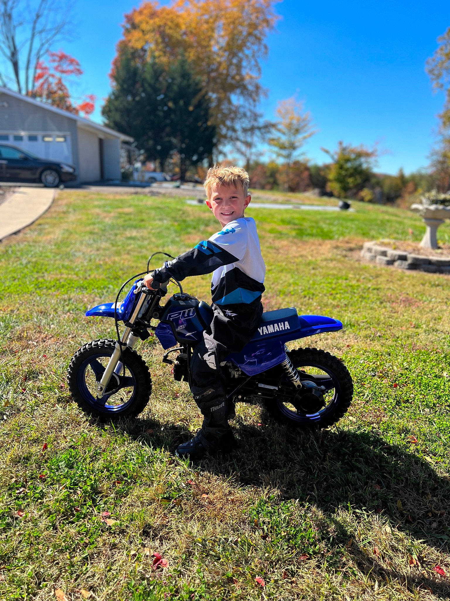 Kade joined the competition — help win amazing prizes! automotive_tire, fender, grass, grassland, joy, landscape, motocross, motor_vehicle, motorcycle, person, plant, racing, rim, rolling, rural_area, sky, spoke, tire, toddler, tree