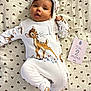 baby, infant, newborn, bambi_onesie, headband, blanket, heart_pattern, milestone_card, text_card, brown_eyes, dark_hair, lying_down, cute, portrait, soft_texture, bedroom, open_mouth, smiling, cozy, hands
