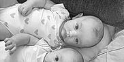Evy Et Lylou participe au concours pour gagner de l'argent avec cette photo : baby, black_and_white, child, closeup, cozy, cute, face, heart_pattern, indoor, infant, lying_down, monochrome, newborn, onesie, person, pillow, portrait, soft_texture, toddler, two_babies