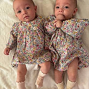 Evy Et Lylou participe au concours pour gagner de l'argent avec cette photo : baby, blanket, child, comfortable, curious, cute, face, floral_dress, footwear, hand, happy, indoor, infant, lying_down, newborn, person, portrait, socks, soft_texture, twin