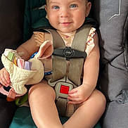 Emily is registered to the contest to win money with this photo: baby, child, car_seat, safety_harness, plush_toy, smiling, blue_eyes, infant, seatbelt, cute, child_safety, soft_toy, pink_clothing, indoor, closeup, person, baby_toy, happy, seat, young_child
