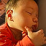 baby, sleeping, infant, orange_clothing, polka_dot, hand, thumb, face, cheek, peaceful, close_up, portrait, skin, cute, child, newborn, rest, cozy, indoors, soft_light