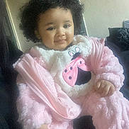 Alyza is registered to the contest to win money with this photo: child, baby, toddler, curly_hair, pink_outfit, plush, onesie, smile, sitting, couch, indoor, portrait, hand, cheeks, cozy, fuzzy_texture, home_interior, soft_lighting, adorable, clothing