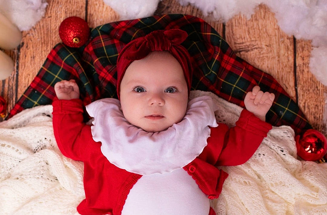 Gabrielle a rejoint le concours — aidez-le/la à gagner de superbes lots ! baby, baby_toddler_clothing, cheek, child, comfort, dress, face, hand, happy, head, headwear, linens, pattern, person, plaid, product, red, skin, sleeve, tartan