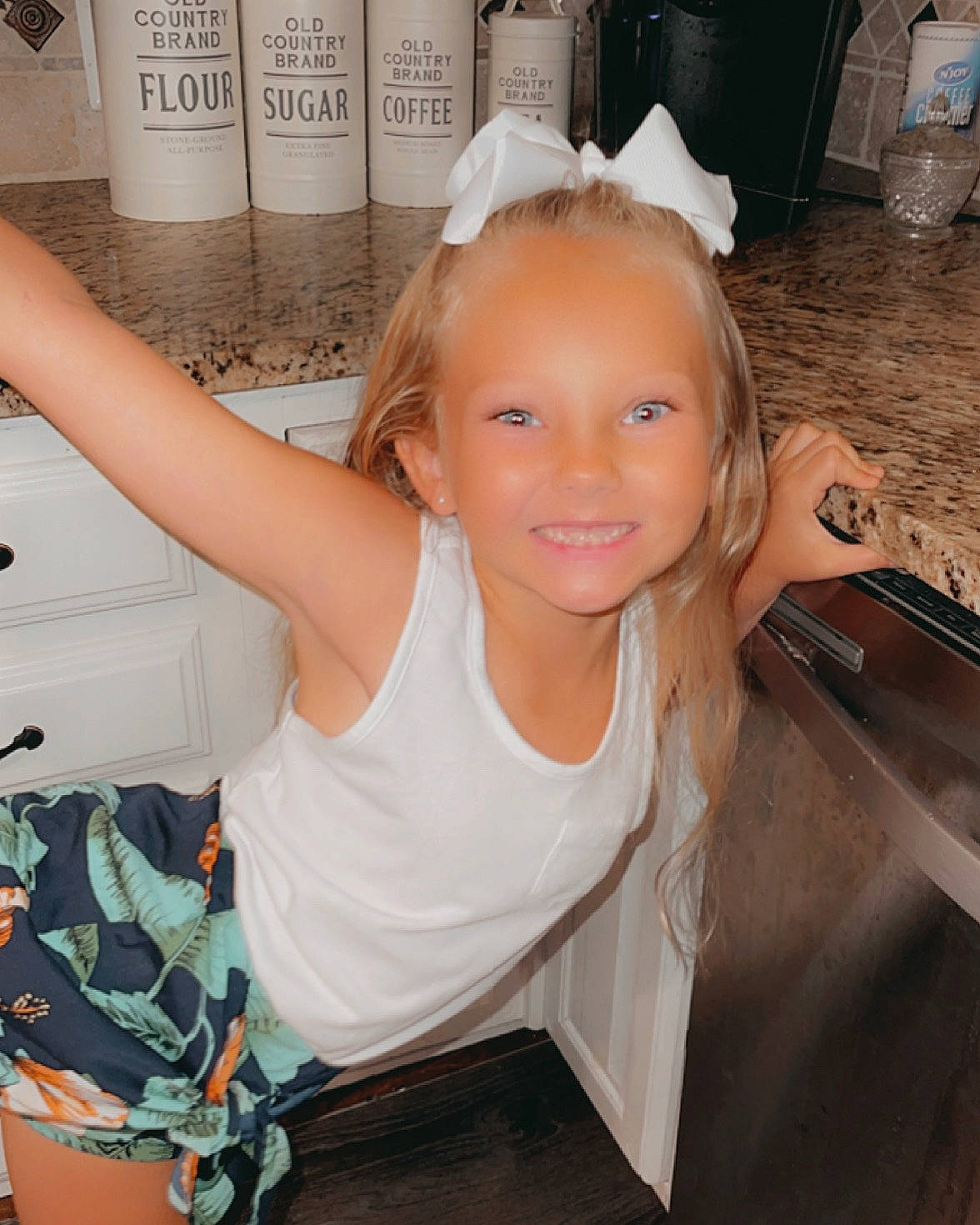 Makayla is registered to the contest to win money with this photo: blond, chair, child, finger, fun, gesture, hairstyle, happy, headpiece, joy, person, plate, room, sitting, smile, standing, t_shirt, table, thigh, thumb