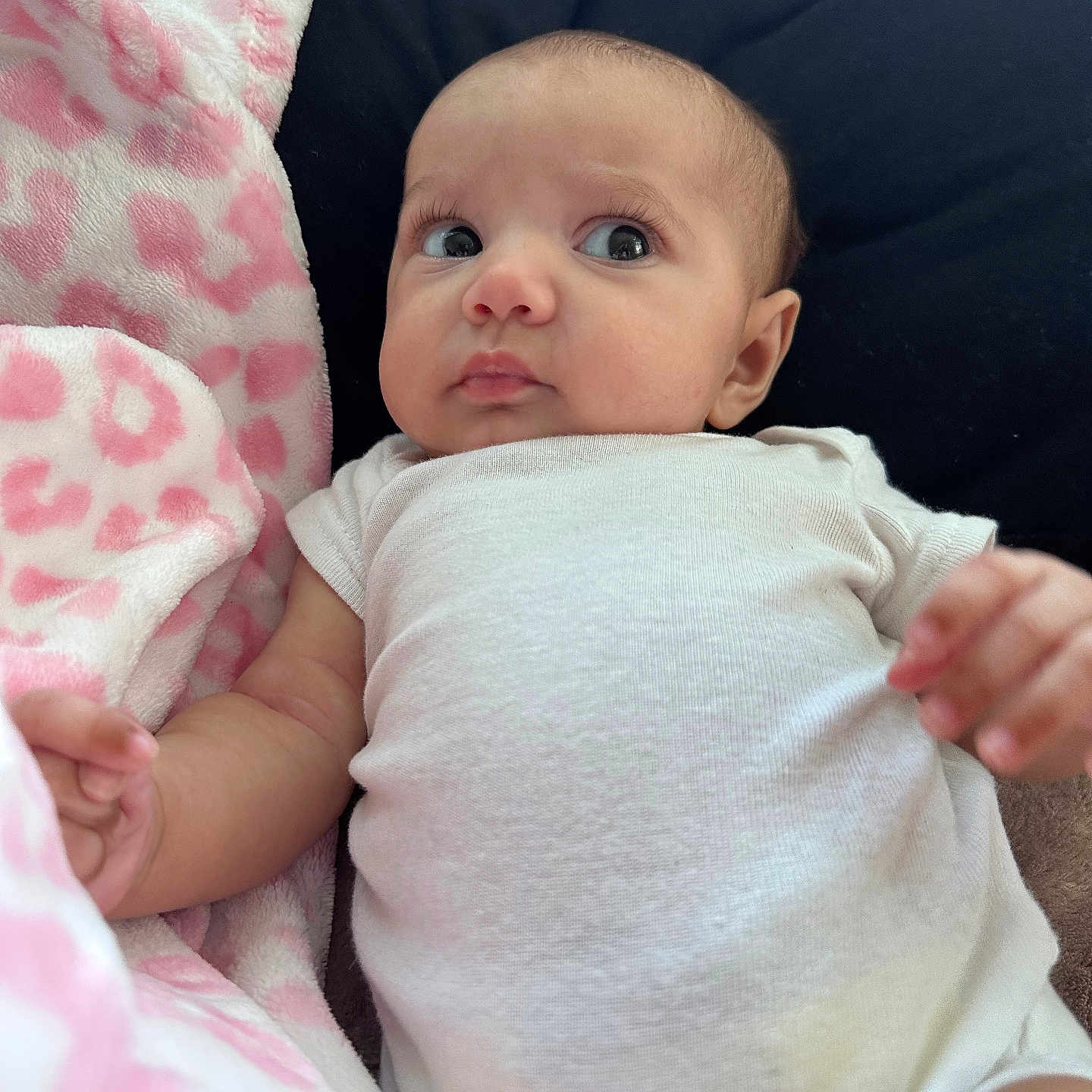 Ahzurai is registered to the contest to win money with this photo: baby, blanket, comfortable, couch, cozy, curious, expression, face, hand, head, indoor, infant, laying_down, person, pink_pattern, portrait, skin, soft_texture, white_onesie, young_child