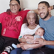 Z'Uriel is registered to the contest to win money with this photo: family, multigenerational, baby, elderly_woman, man, adult, couch, living_room, portrait, smile, glasses, cap, beard, holding, sitting, casual_clothing, hand, indoors, closeup, skin_tone