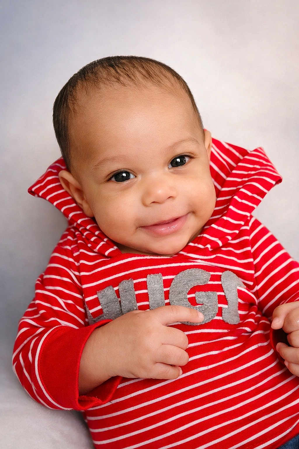 Z'Uriel is registered to the contest to win money with this photo: baby, infant, smile, portrait, red_striped_shirt, clothing, hand, eye_contact, close_up, soft_background, cute, adorable, cheeks, head, face, skin, sleeve, young_child, studio_photo, happy