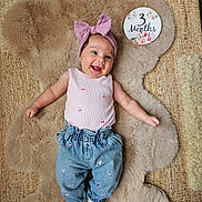 Lya participe au concours pour gagner de l'argent avec cette photo : baby, infant, smiling, headband, bow, jeans, pink_top, socks, fluffy_rug, milestone_card, 3_months, cute, happy, portrait, clothing, floor, decor, child, infant_girl, lying_down