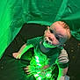 baby, pacifier, crawling, green_light, tent, curious, child, indoors, glowing_lights, striped_pants, sock, hand, face, person, infant, playing, soft_fabric, young_child, expression, bright_colors