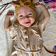 Elena is registered to the contest to win money with this photo: baby, smiling, head_wrap, floral_outfit, blanket, lying_down, happy, infant, cute, child, pattern, soft_texture, raised_arms, portrait, buttoned_clothing, indoors, light, skin, face, expression
