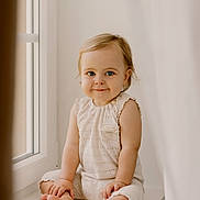 Cassie participe au concours pour gagner de l'argent avec cette photo : toddler, child, baby, sitting, window, natural_light, smiling, blue_eyes, cute, innocence, portrait, indoor, soft_light, cream_outfit, happy, young_child, face, barefoot, cute_expression, curious