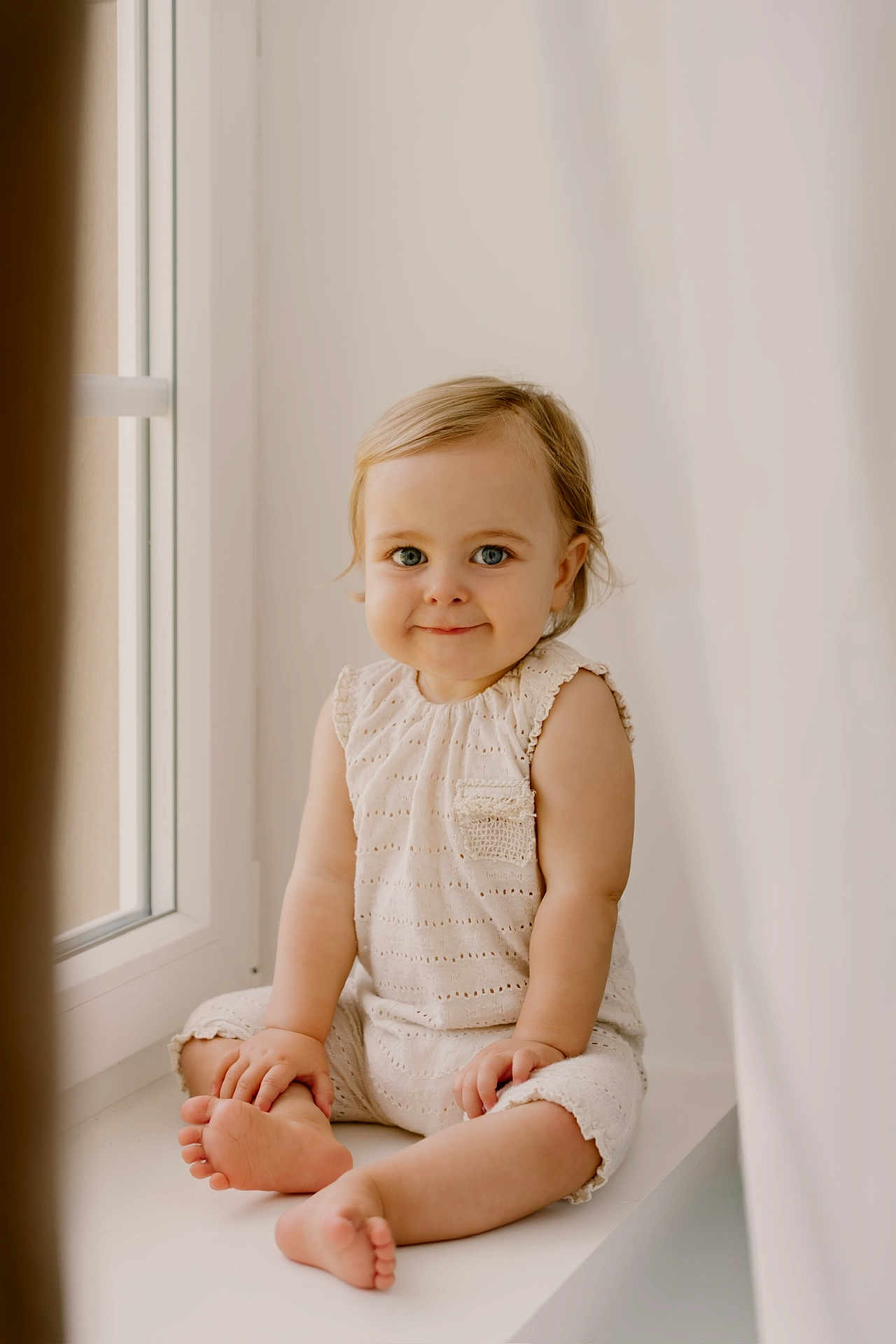 Cassie participe au concours pour gagner de l'argent avec cette photo : toddler, child, baby, sitting, window, natural_light, smiling, blue_eyes, cute, innocence, portrait, indoor, soft_light, cream_outfit, happy, young_child, face, barefoot, cute_expression, curious