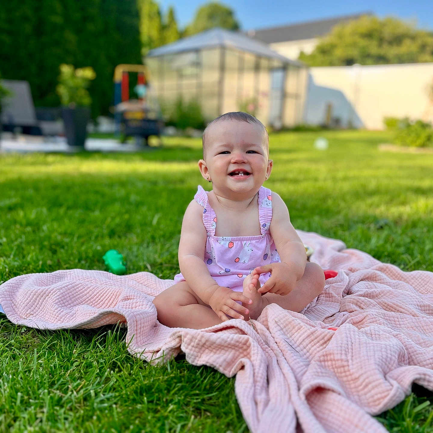 Isabella is registered to the contest to win money with this photo: baby, backyard, blanket, child, cute, daytime, garden, grass, greenery, happy, infant, nature, outdoor, playing, portrait, sitting, smiling, summer, sunlight, toys