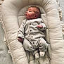 newborn, baby, onesie, baby_lounger, soft_texture, neutral_colors, infant, sleepwear, cushion, cozy, curious, indoor, carpet, small_hands, footwear, sleeping_area, calm, child, portrait, resting