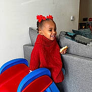 Colette is registered to the contest to win money with this photo: bread, child, clothing, couch, face, female, food, furniture, girl, hair, happy, head, indoors, knitwear, person, photography, portrait, sitting, smile, sweater
