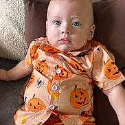 Jalen joined the competition — help win amazing prizes! baby, child, pumpkin_shirt, orange_shorts, cushion, sofa, blue_eyes, curly_hair, casual_clothing, indoor, relaxed, portrait, cute, festive, halloween_theme, infant, comfortable, soft_lighting, closeup, person