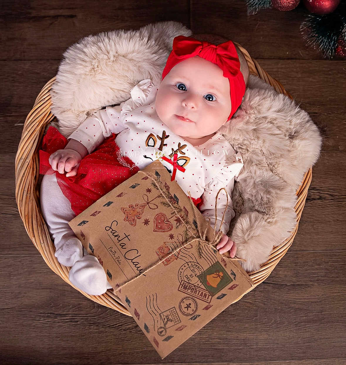 Dolly is registered to the contest to win money with this photo: baby, infant, basket, red_headband, white_clothing, holiday, christmas, envelope, letter, wooden_floor, fluffy_blanket, cute, festive, child, lying_down, portrait, holiday_decoration, cozy, toddler, gift