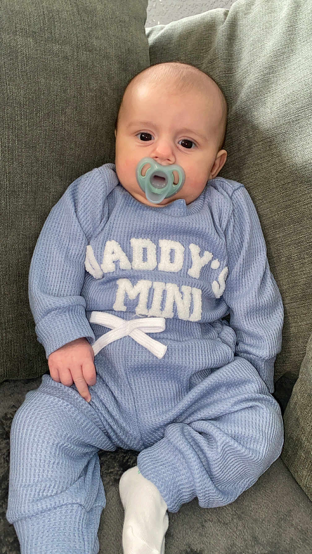Brodie is registered to the contest to win money with this photo: baby, infant, pacifier, blue_outfit, sitting, couch, cozy, child, cute, indoor, clothing, face, person, young, small, sock, relaxed, home, portrait, casual