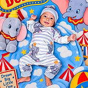 Adriana joined the competition — help win amazing prizes! baby, baby_clothing, beach_ball, blanket, blue, child, circus, clouds, colorful, dumbo, elephant, hat, infant, lying_down, nursery, portrait, smiling, stars, stuffed_animal, toy