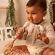 Noa a rejoint le concours — aidez-le/la à gagner de superbes lots ! baby, cake, frosting, wooden_spoon, messy, celebration, birthday, child, indoor, smiling, cute, white_clothing, sitting, face, hand, food, happy, decor, greenery, portrait