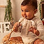 baby, birthday, cake, celebration, child, cute, decor, face, food, frosting, greenery, hand, happy, indoor, messy, portrait, sitting, smiling, white_clothing, wooden_spoon
