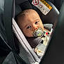 baby, car_seat, pacifier, child, infant, seatbelt, close_up, indoor, warning_label, cute, portrait, young_child, car_interior, person, baby_clothing, head, face, safety, seat, mickey_mouse