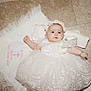 baby, infant, dress, white_dress, lace, headband, floor, tiled_floor, cloth, embroidery, baptism, celebration, cute, child, portrait, laying_down, indoors, person, newborn, ceremony